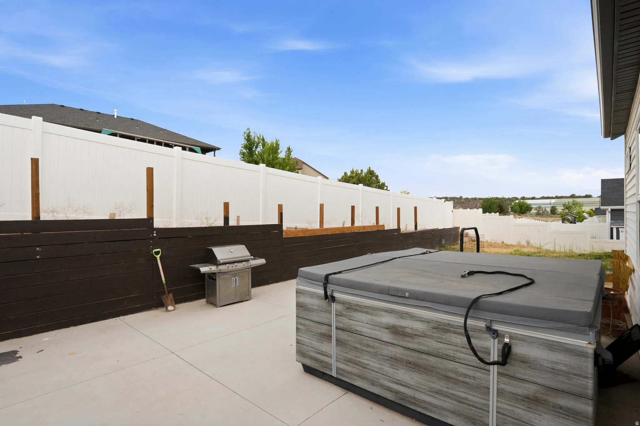 Concrete patio area featuring a white privacy fence with a dark wood-finish base