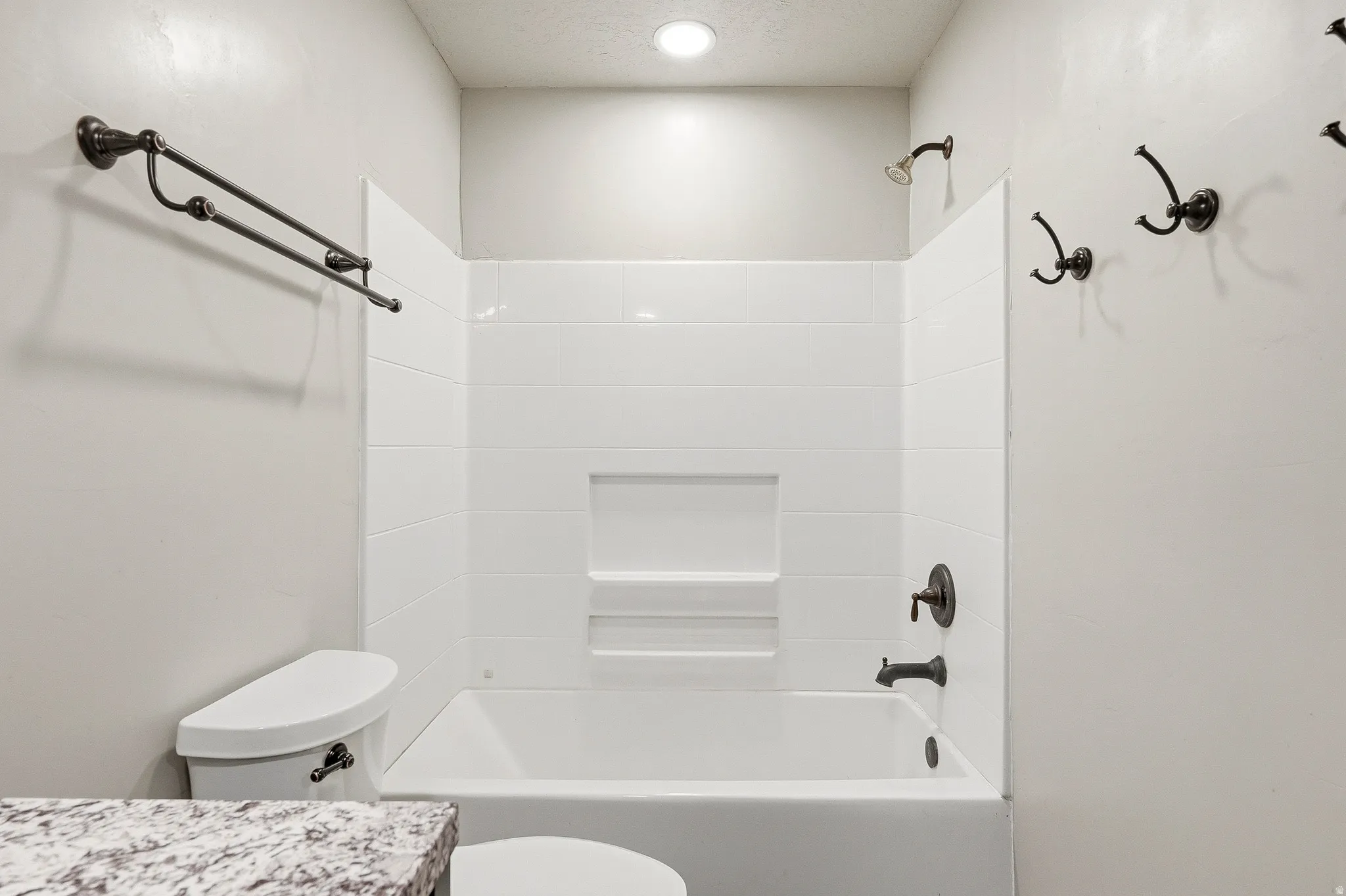 White tub and shower combination with white subway tile surround and integrated shelf niche