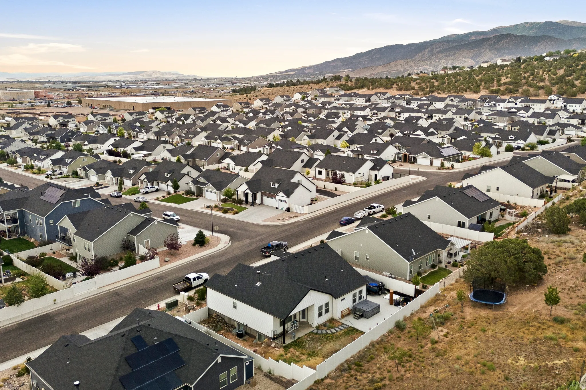 Aerial perspective of a developed residential community featuring an array of single-family homes with dark shingle roofs