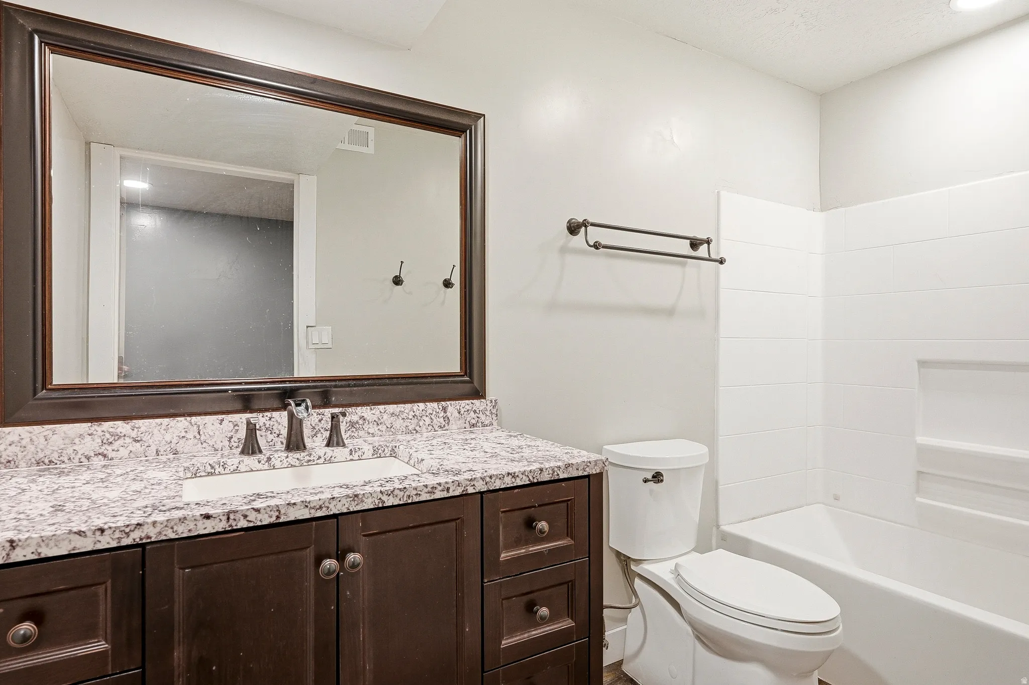 Vanity with a granite-style countertop, undermount sink, and dark wood-finish cabinetry