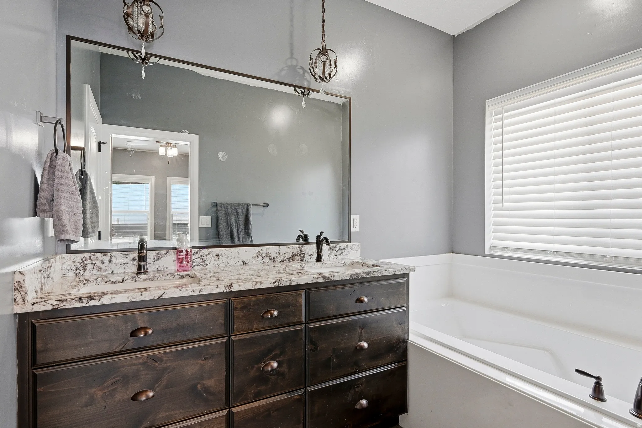 Double vanity featuring a light-toned countertop, dark wood-finish cabinetry, and framed mirror