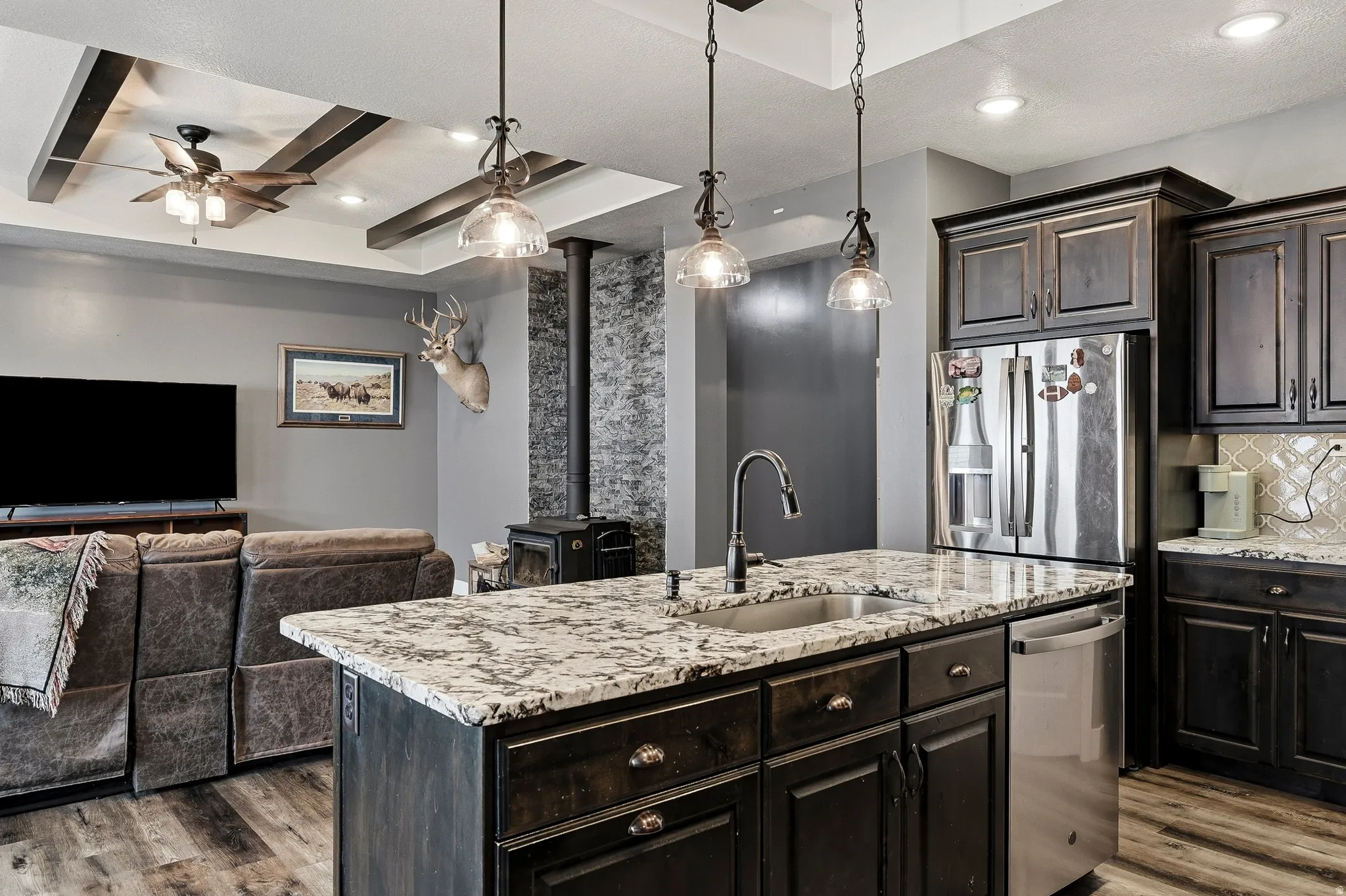 Spacious kitchen island featuring a built-in sink and granite countertop, complemented by dark wood-finish cabinetry