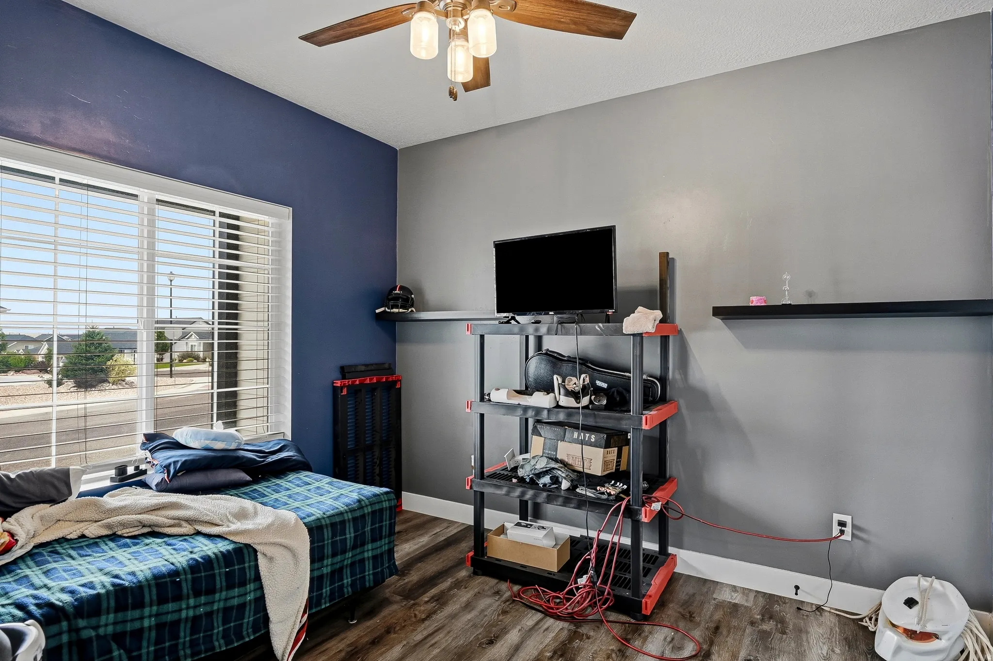 Bedroom featuring wood-finish flooring, a ceiling fan with integrated lighting, and a large window with horizontal blinds