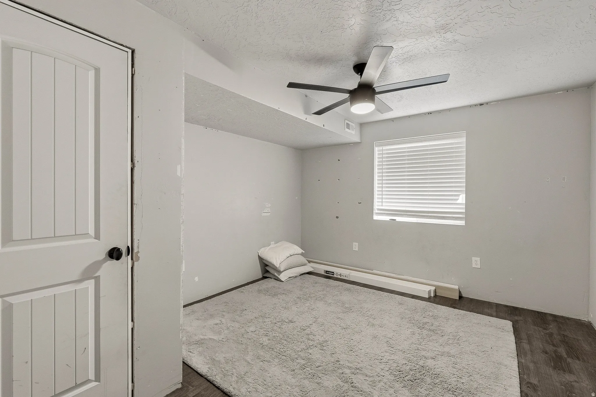 Room featuring wood-finish flooring, a contemporary ceiling fan, and a single window with horizontal blinds