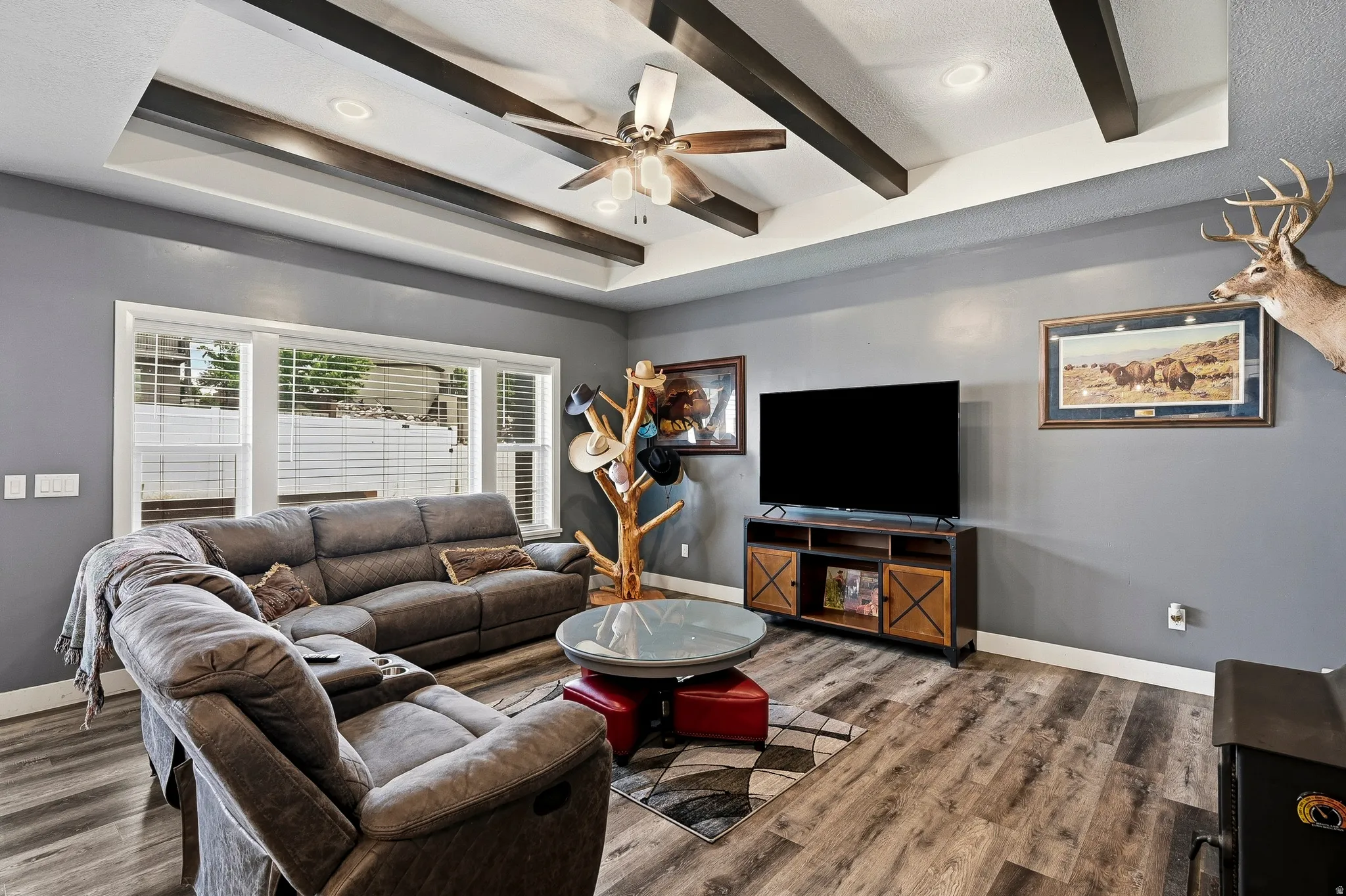 Living area featuring a tray ceiling with exposed dark beams and recessed lighting