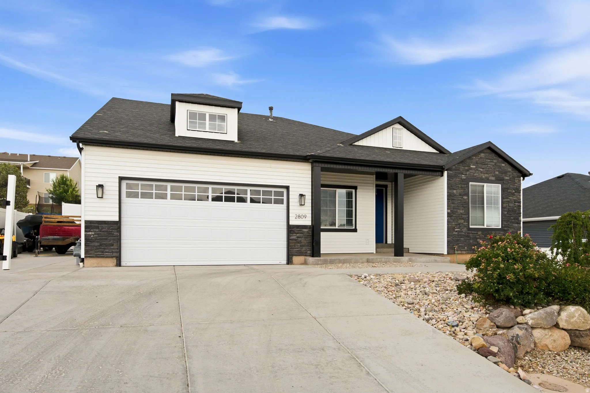 Contemporary exterior featuring white siding, dark stone accents, and a contrasting dark roof