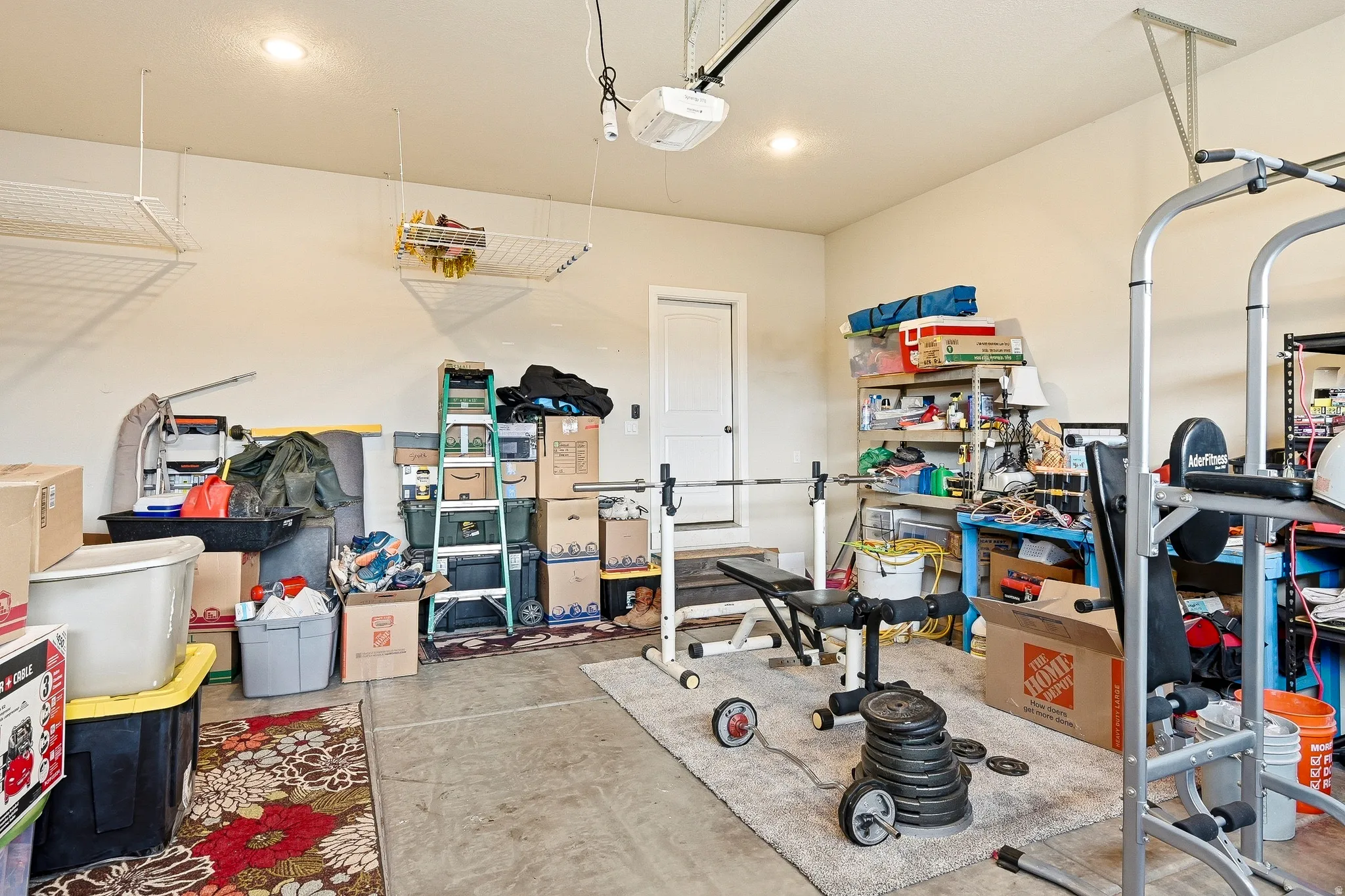 Garage space featuring concrete flooring, recessed lighting, and wall-mounted overhead storage racks