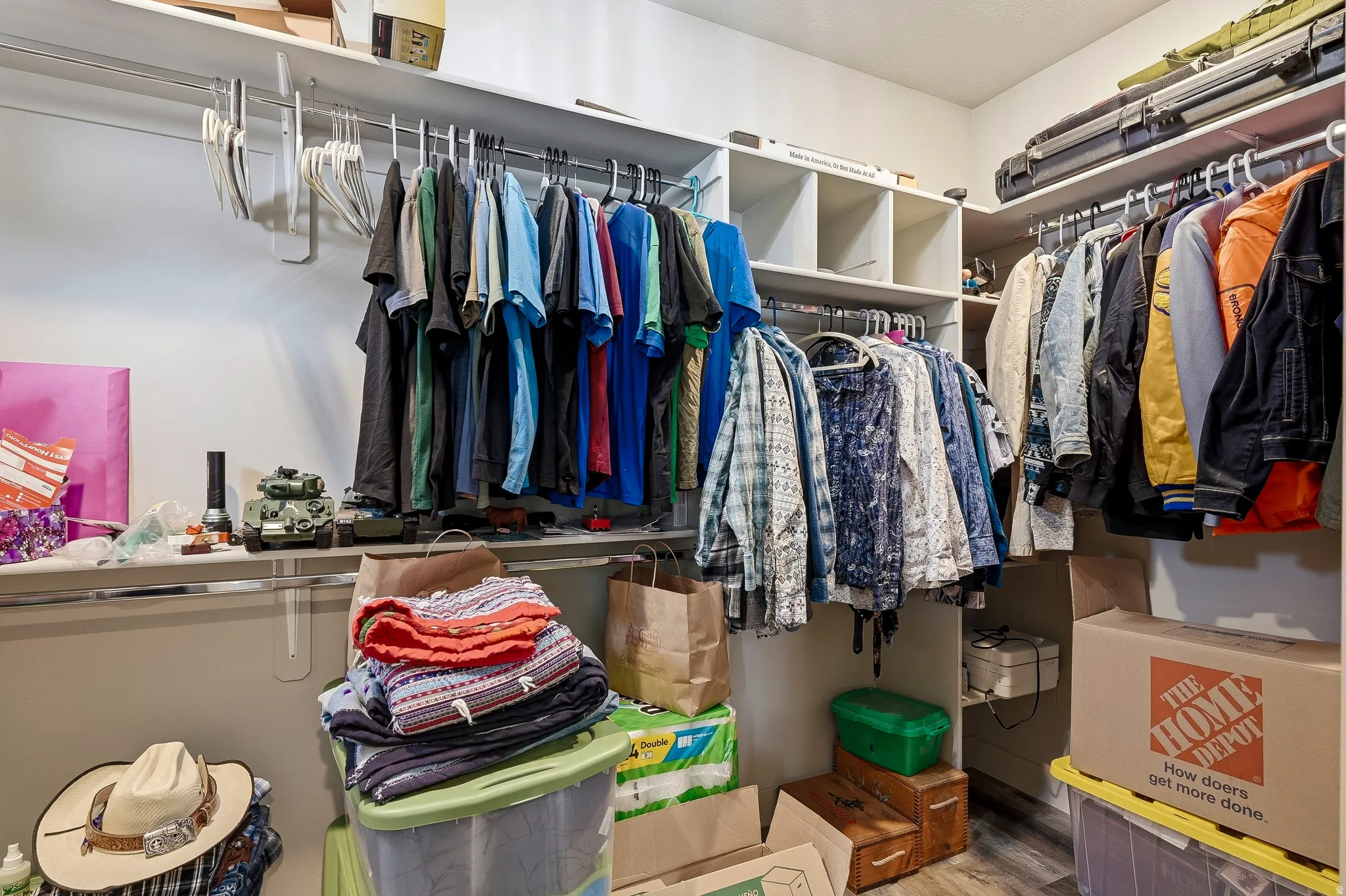 Expansive walk-in closet featuring multiple clothing rods, integrated shelving units, and wood-finish flooring