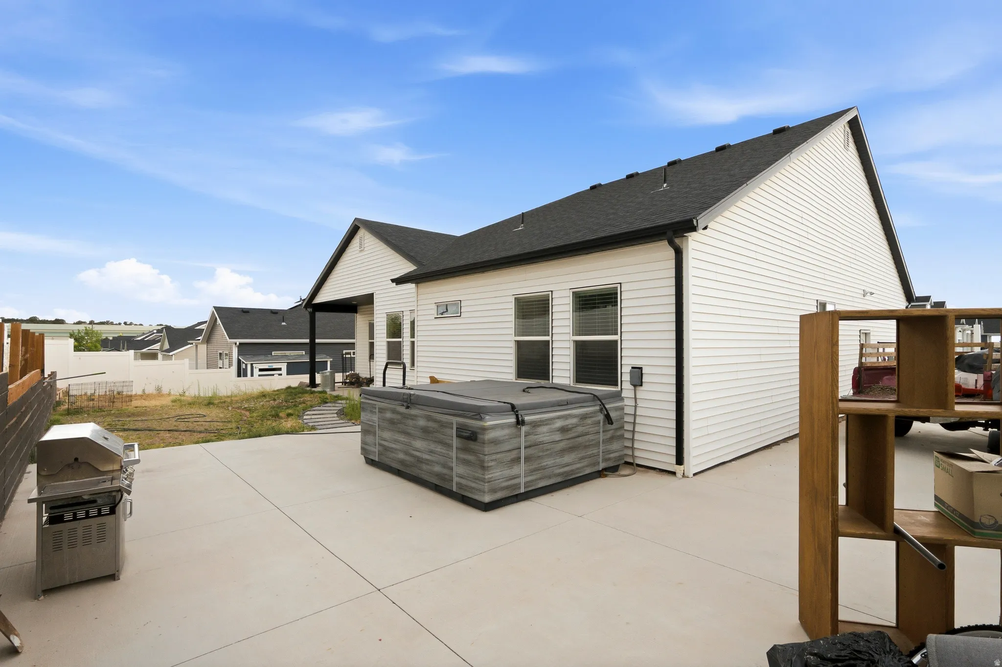 Expansive concrete patio featuring a hot tub with a dark cover