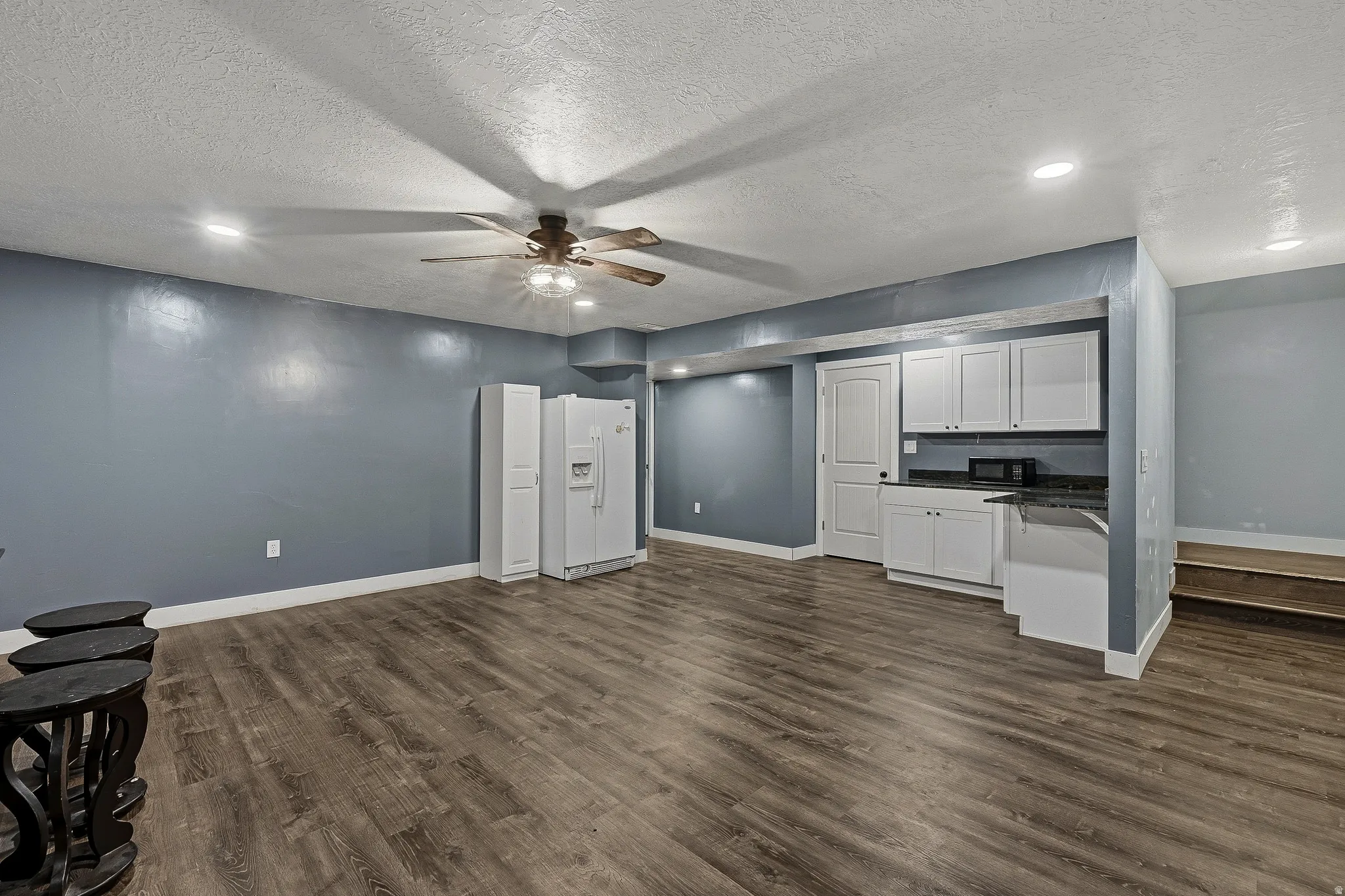 Spacious room featuring wood-finish flooring, recessed lighting, and a ceiling fan