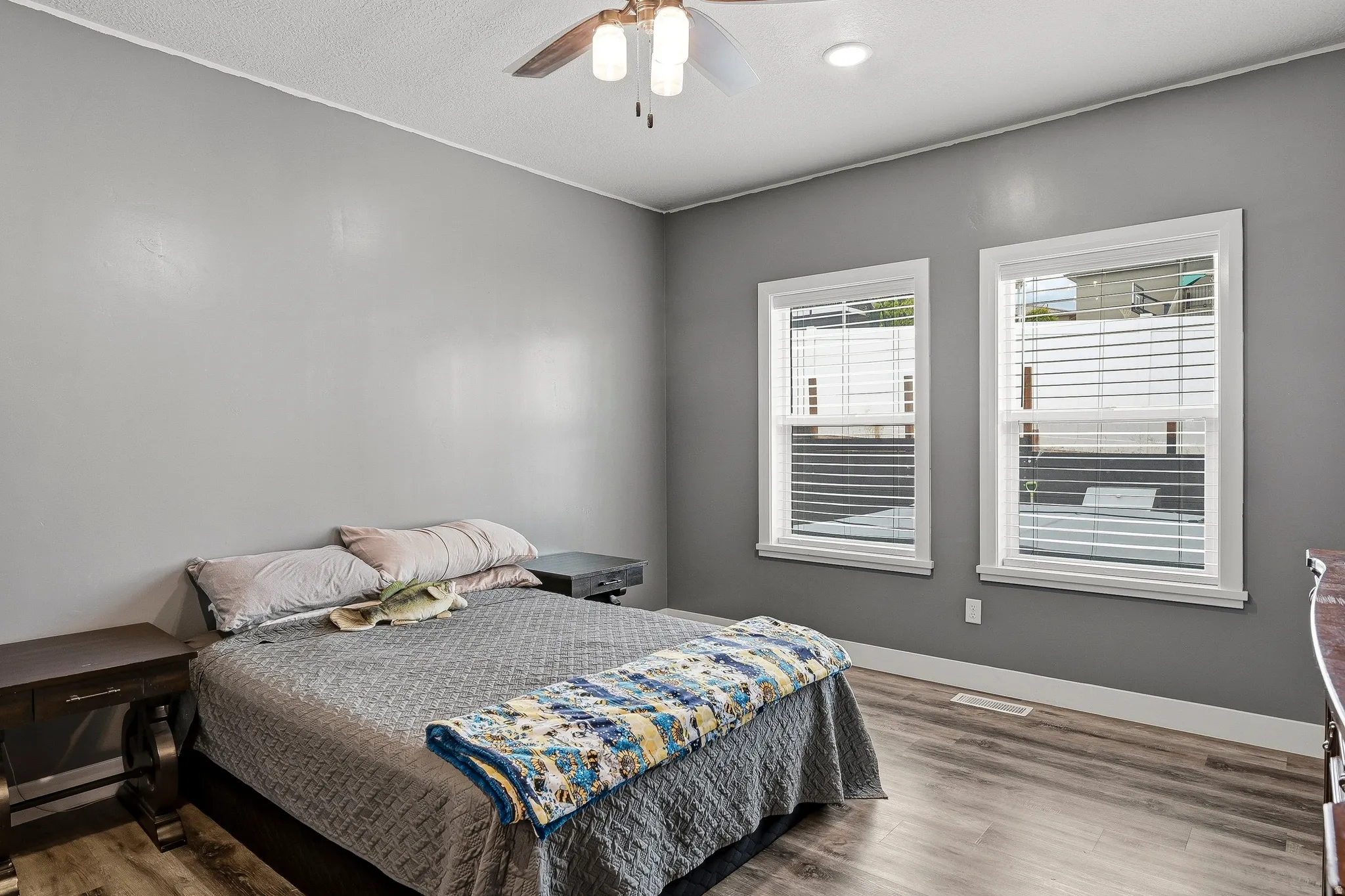 Bedroom featuring wood-finish flooring, two large windows with blinds, a ceiling fan, and recessed lighting