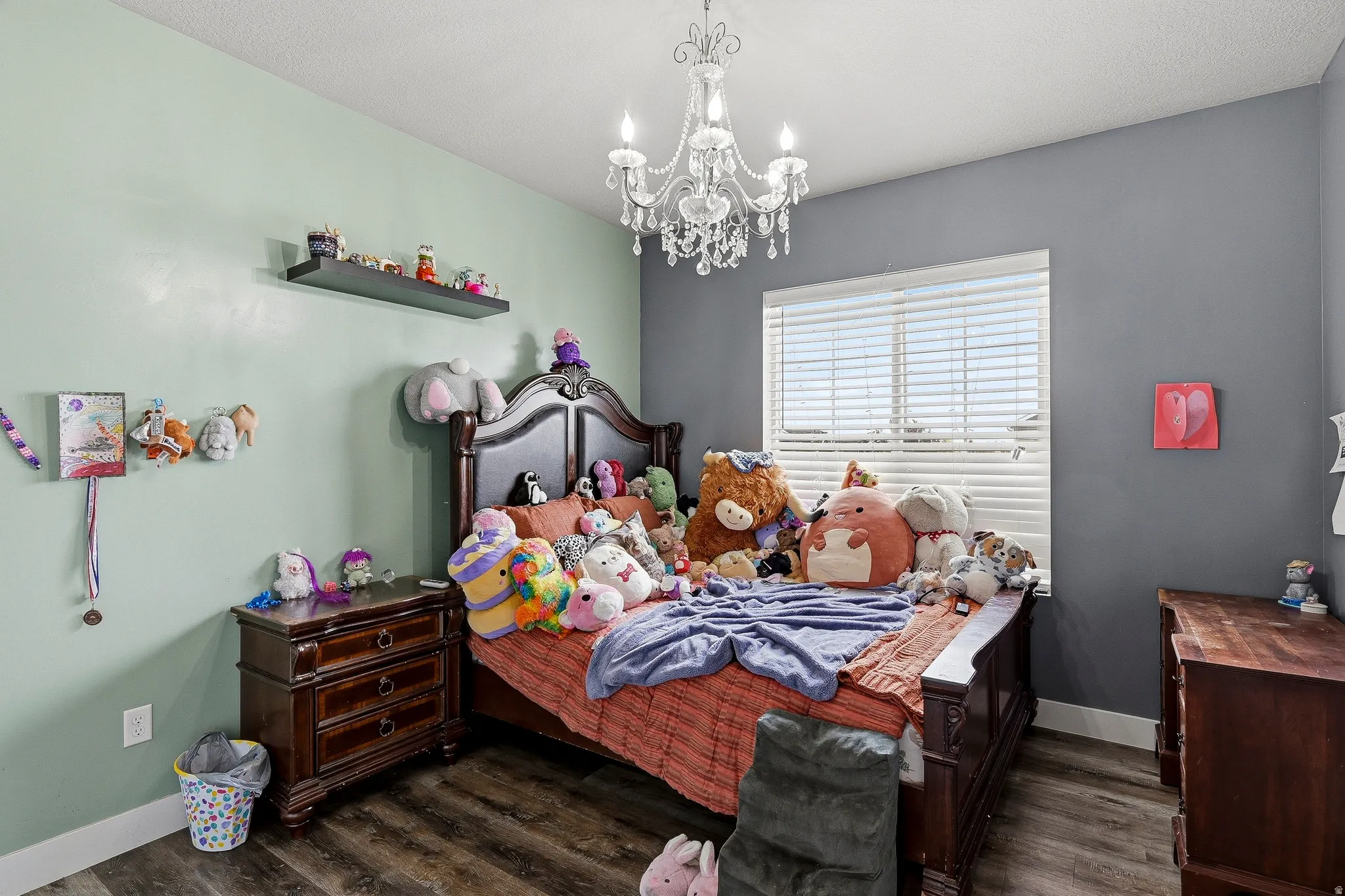 Room featuring wood-finish flooring, a decorative chandelier, and a window with horizontal blinds