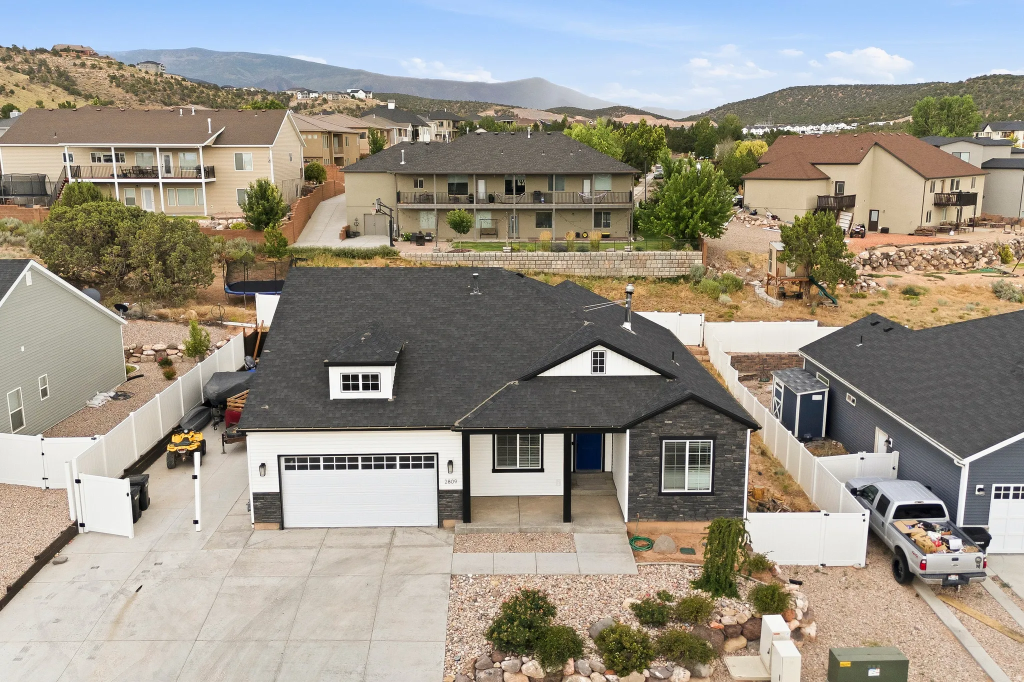 Contemporary single-story home featuring a dark shingle roof, white siding, and a stone facade accent