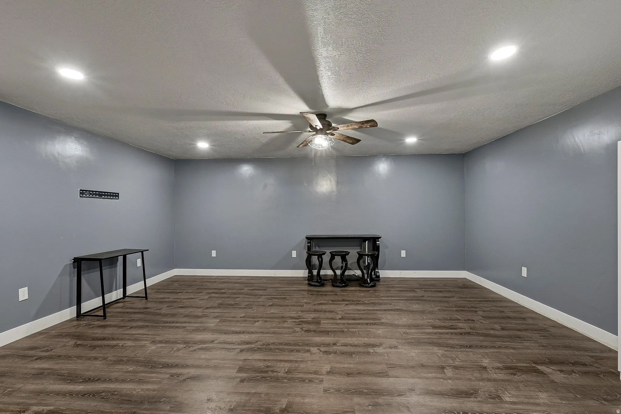 Spacious room with wood-finish flooring, recessed lighting, and a ceiling fan
