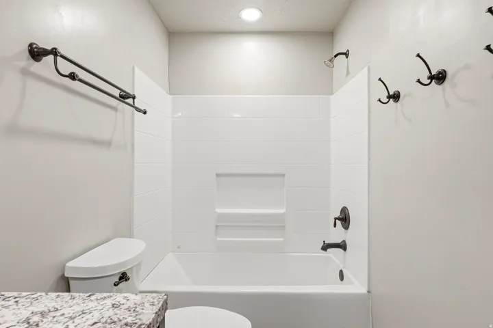 White tub and shower combination with white subway tile surround and integrated shelf niche