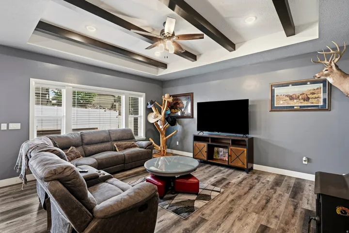 Living area featuring a tray ceiling with exposed dark beams and recessed lighting