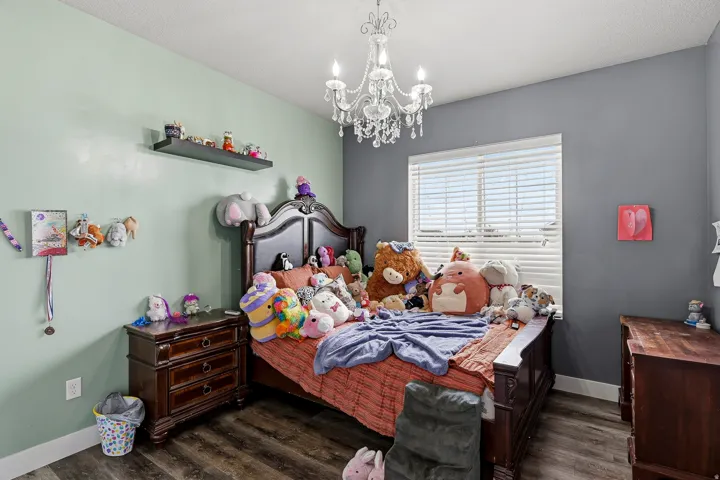 Room featuring wood-finish flooring, a decorative chandelier, and a window with horizontal blinds