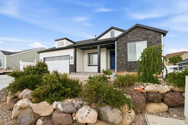 Contemporary exterior featuring white siding and dark stone facade accents