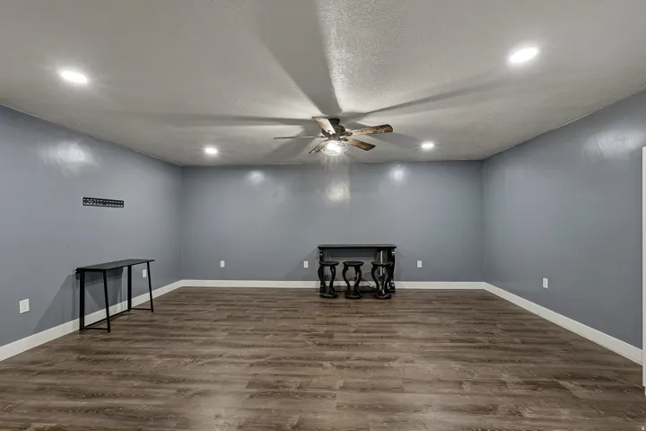 Spacious room with wood-finish flooring, recessed lighting, and a ceiling fan