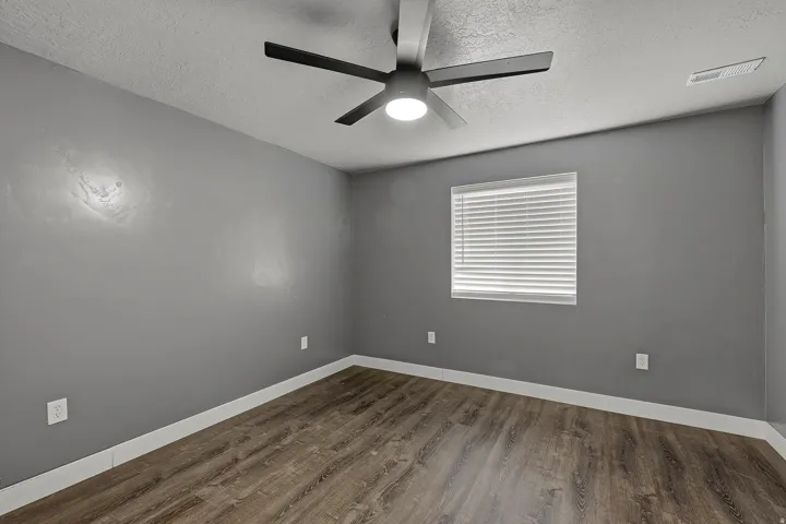 Room featuring wood-finish flooring, a contemporary ceiling fan with integrated lighting, window blinds, and white baseboards