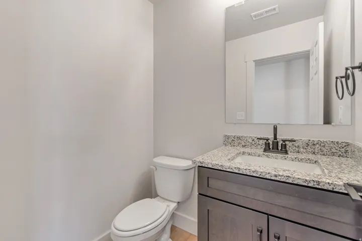Bathroom featuring a dark wood-finish vanity with a granite countertop, undermount sink, and matte black faucet