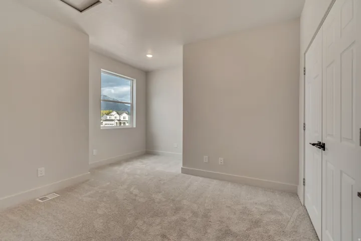 Carpeted room featuring a double-pane window, recessed lighting, and a white bi-fold closet door with black hardware