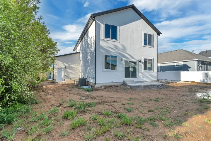 Rear elevation featuring white stucco siding, black trim, and a concrete patio