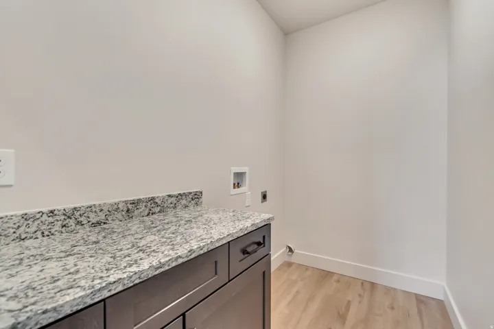 Utility area featuring a speckled countertop, dark wood-finish cabinetry, and wood-finish flooring