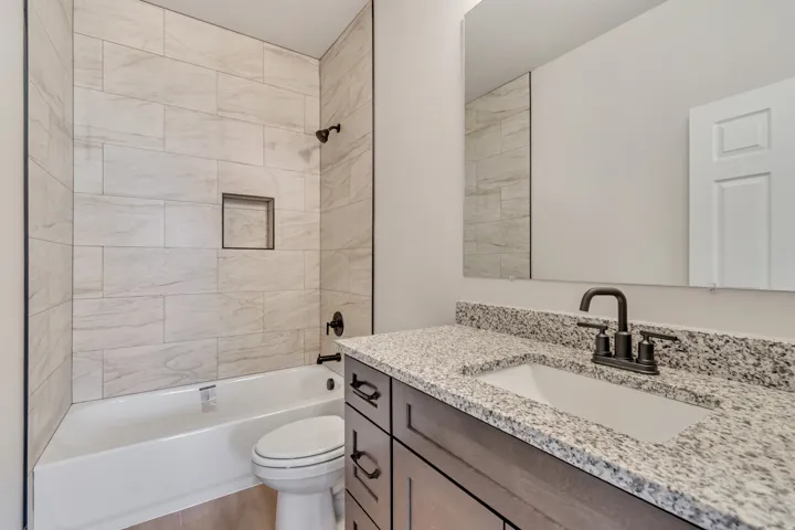 Bathroom vanity featuring a granite countertop with an undermount sink and matte black faucet