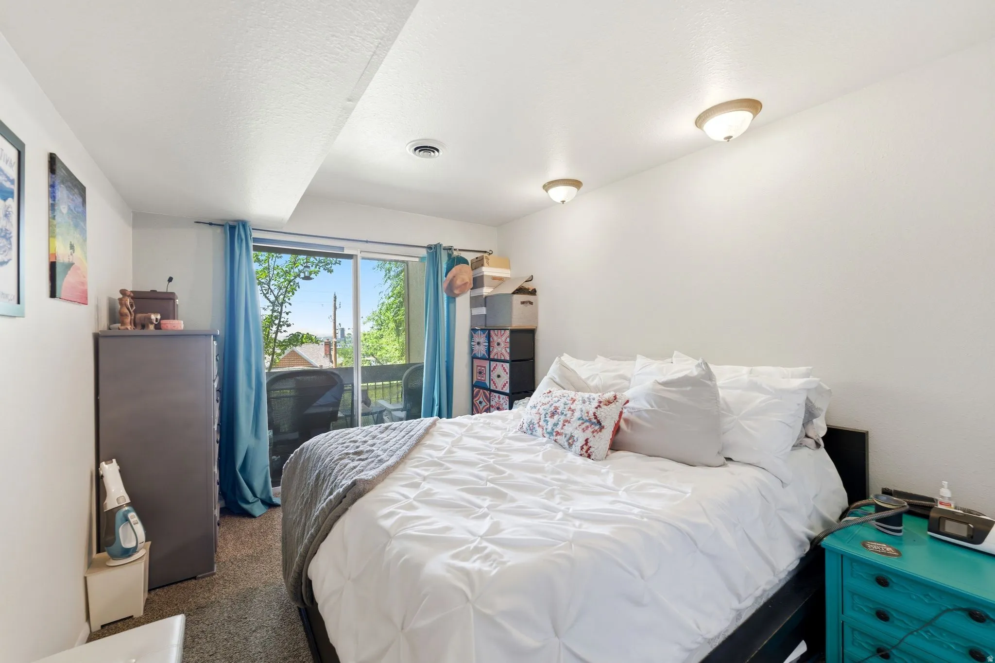 Bedroom featuring a sliding glass door to a private balcony, neutral wall paint, and overhead lighting fixtures