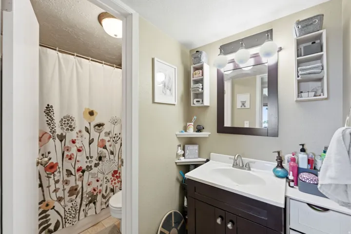 Bathroom featuring a wood-finish vanity with a white countertop and integrated sink, framed mirror, and chrome-finish faucet