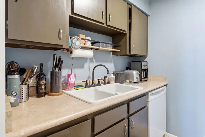 Kitchen featuring a double basin sink, neutral-toned countertops, and painted cabinetry