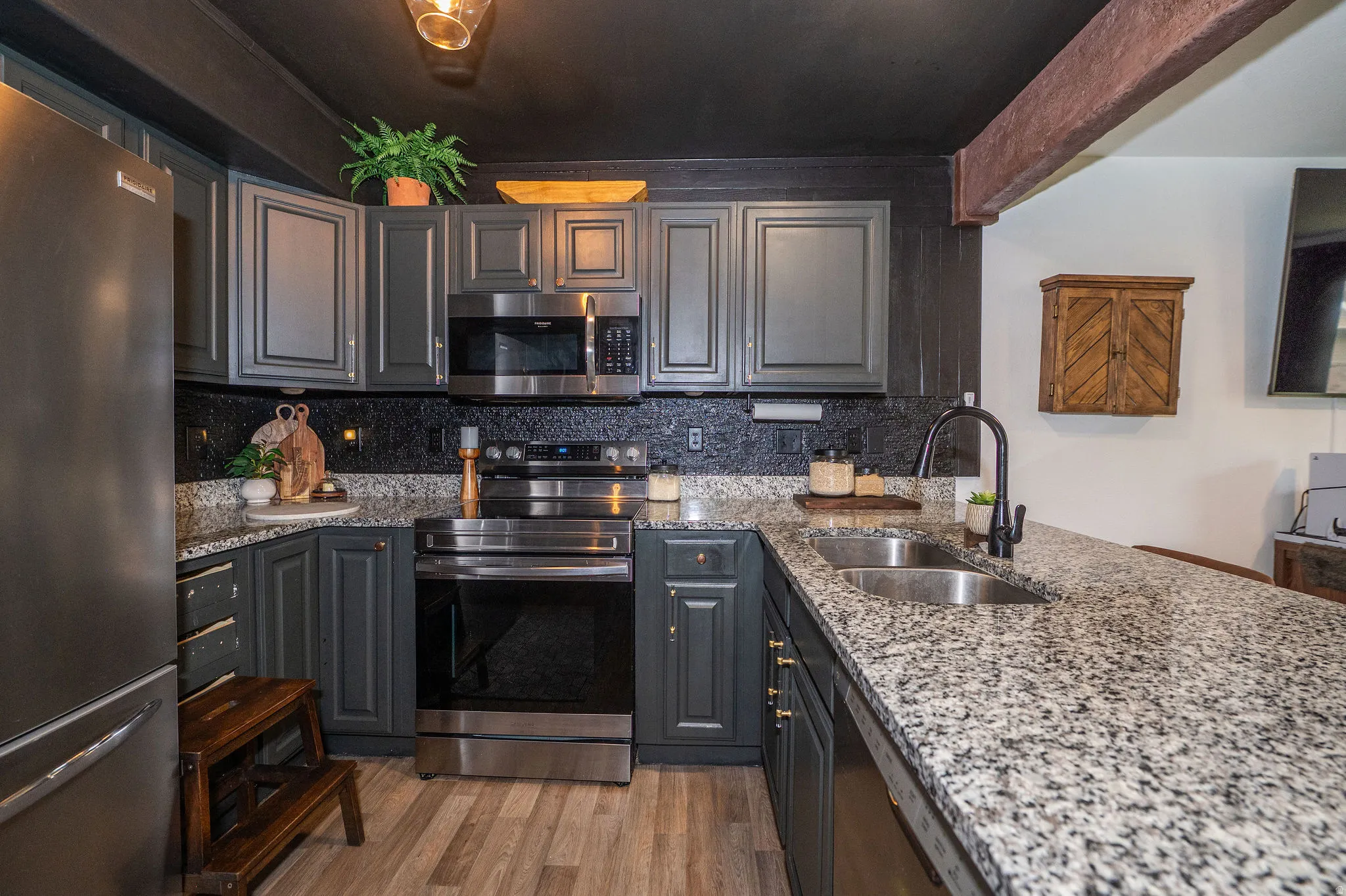 Contemporary kitchen featuring dark cabinetry, granite countertops, and stainless steel appliances