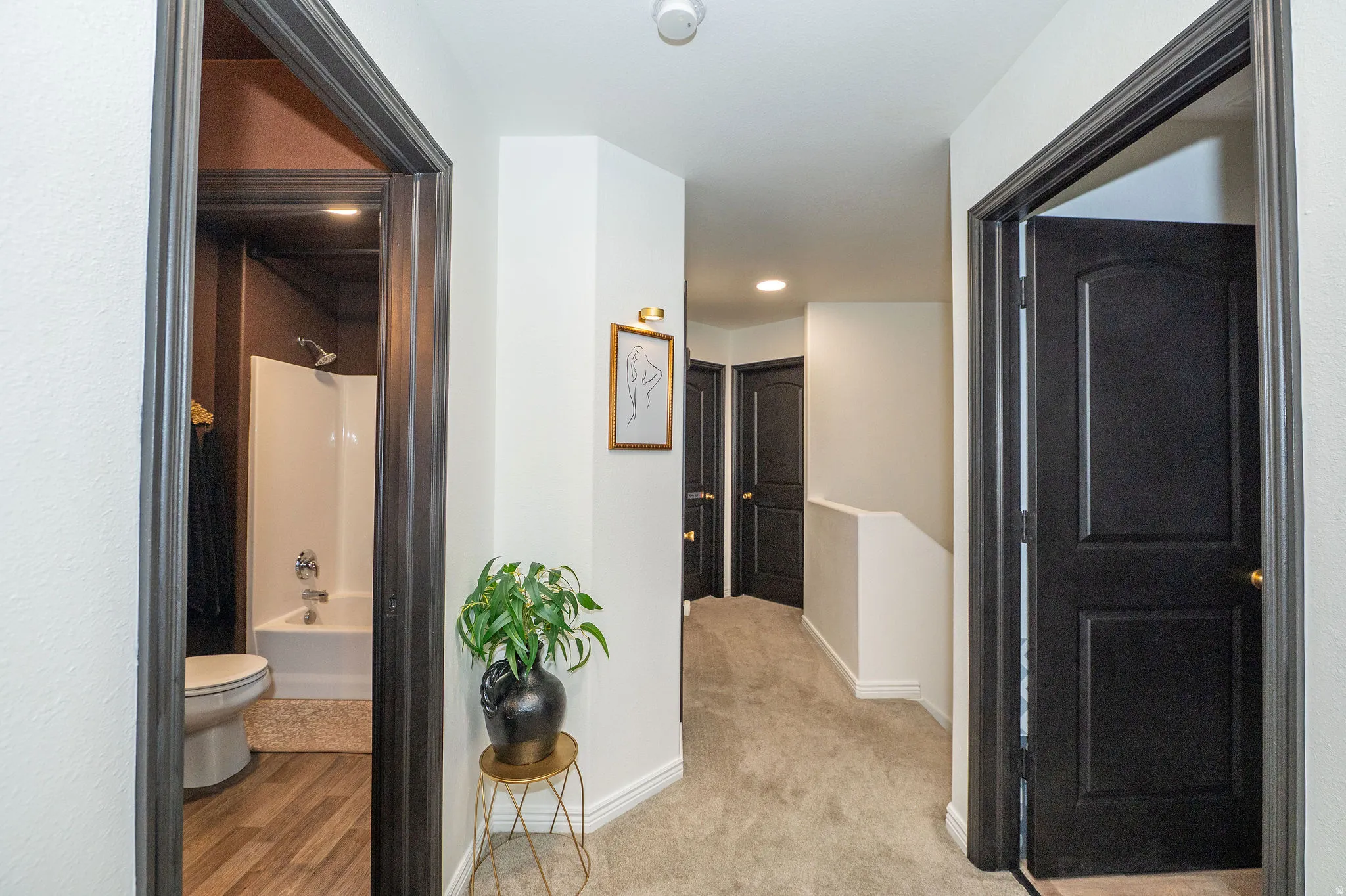 Hallway featuring neutral-toned carpet flooring, white walls, and dark trim