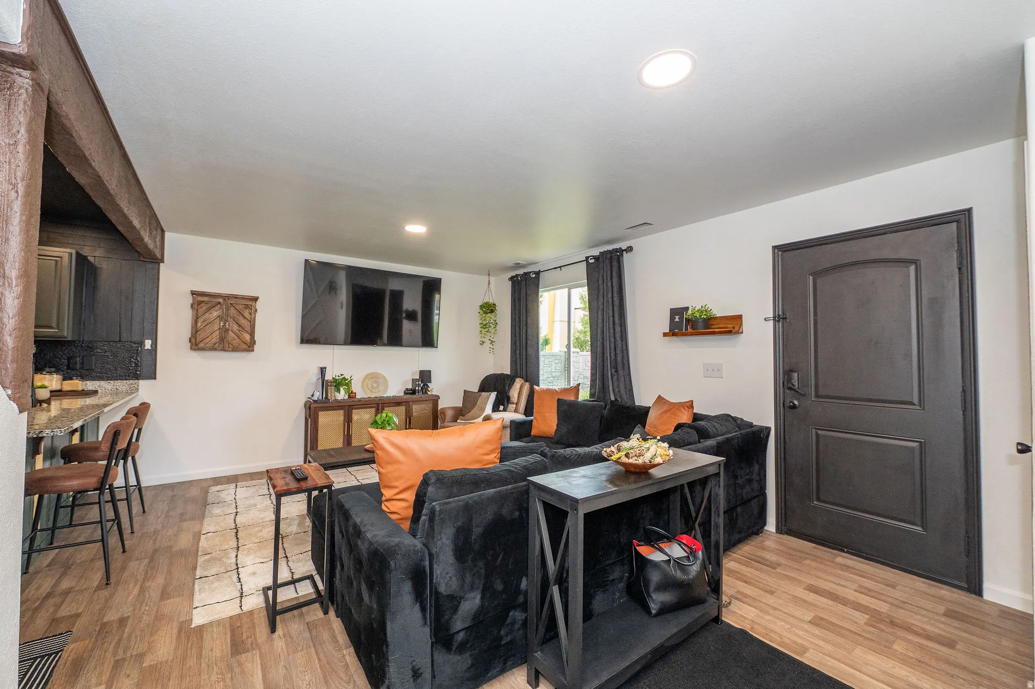 Open-concept living space featuring wood-finish flooring, recessed lighting, and a dark paneled door