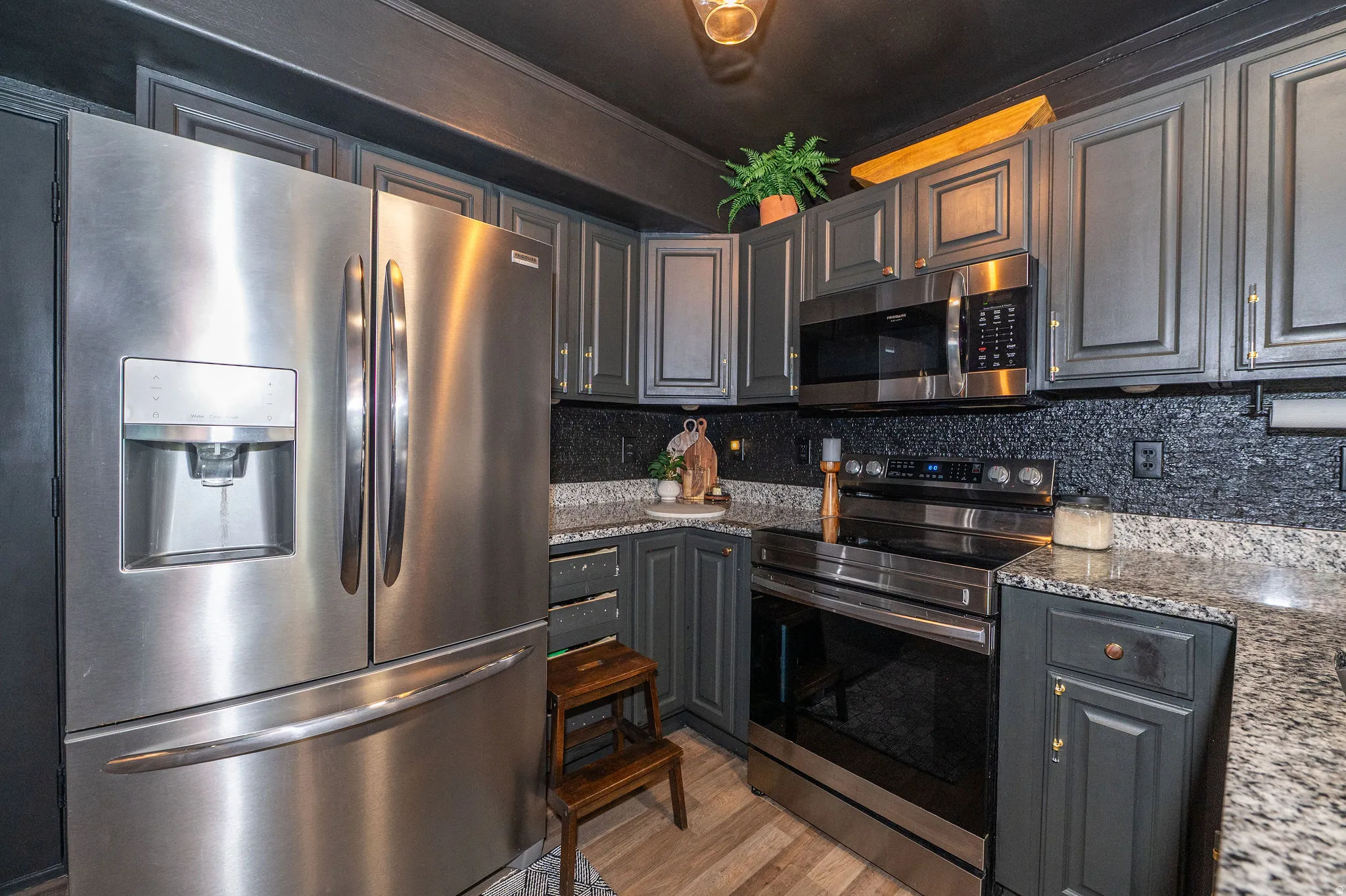 Kitchen featuring stainless steel appliances, dark cabinetry, light-colored countertops, and a textured backsplash