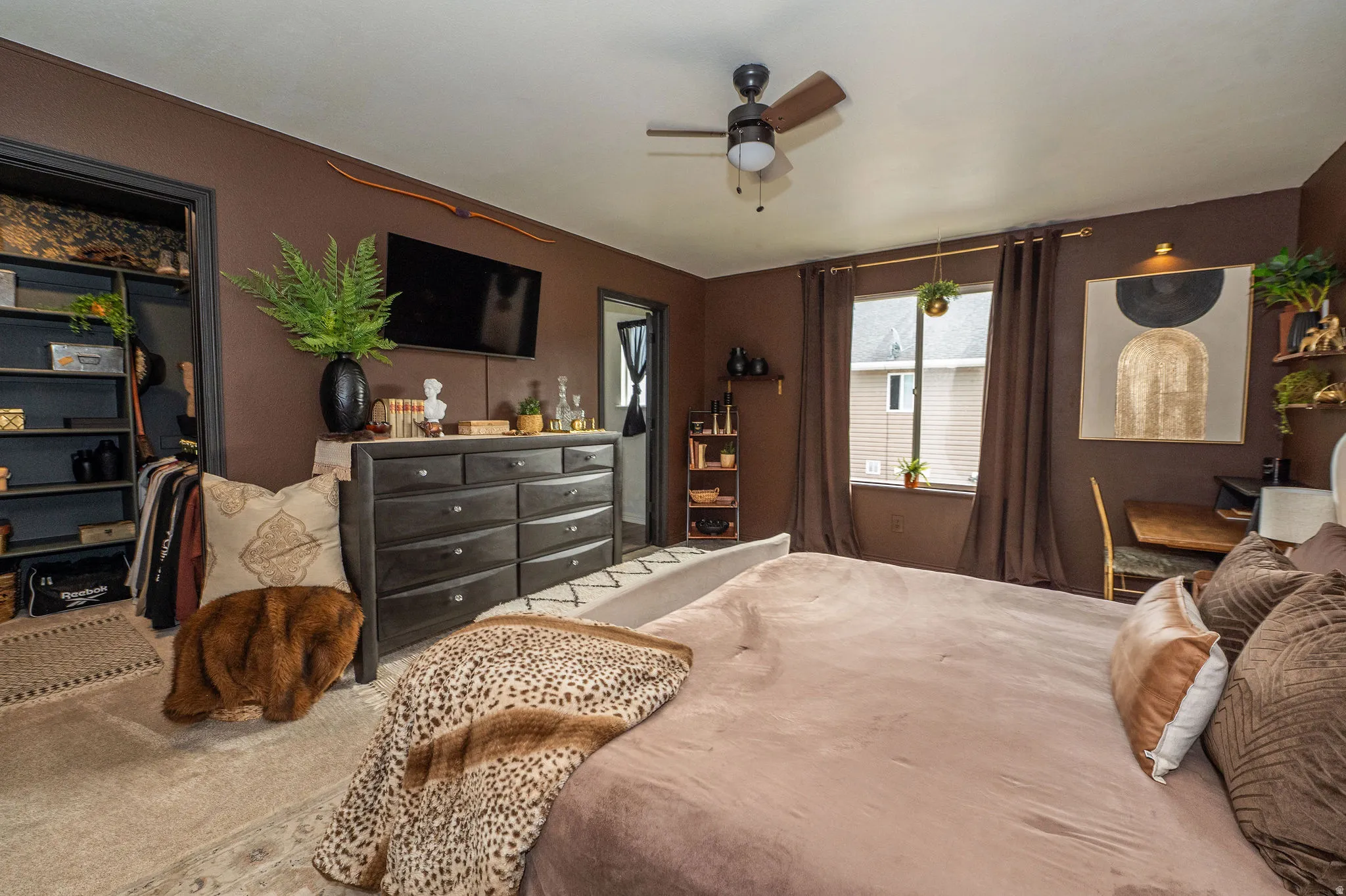 Bedroom featuring a ceiling fan, a window with curtain rods, a built-in closet with shelving,