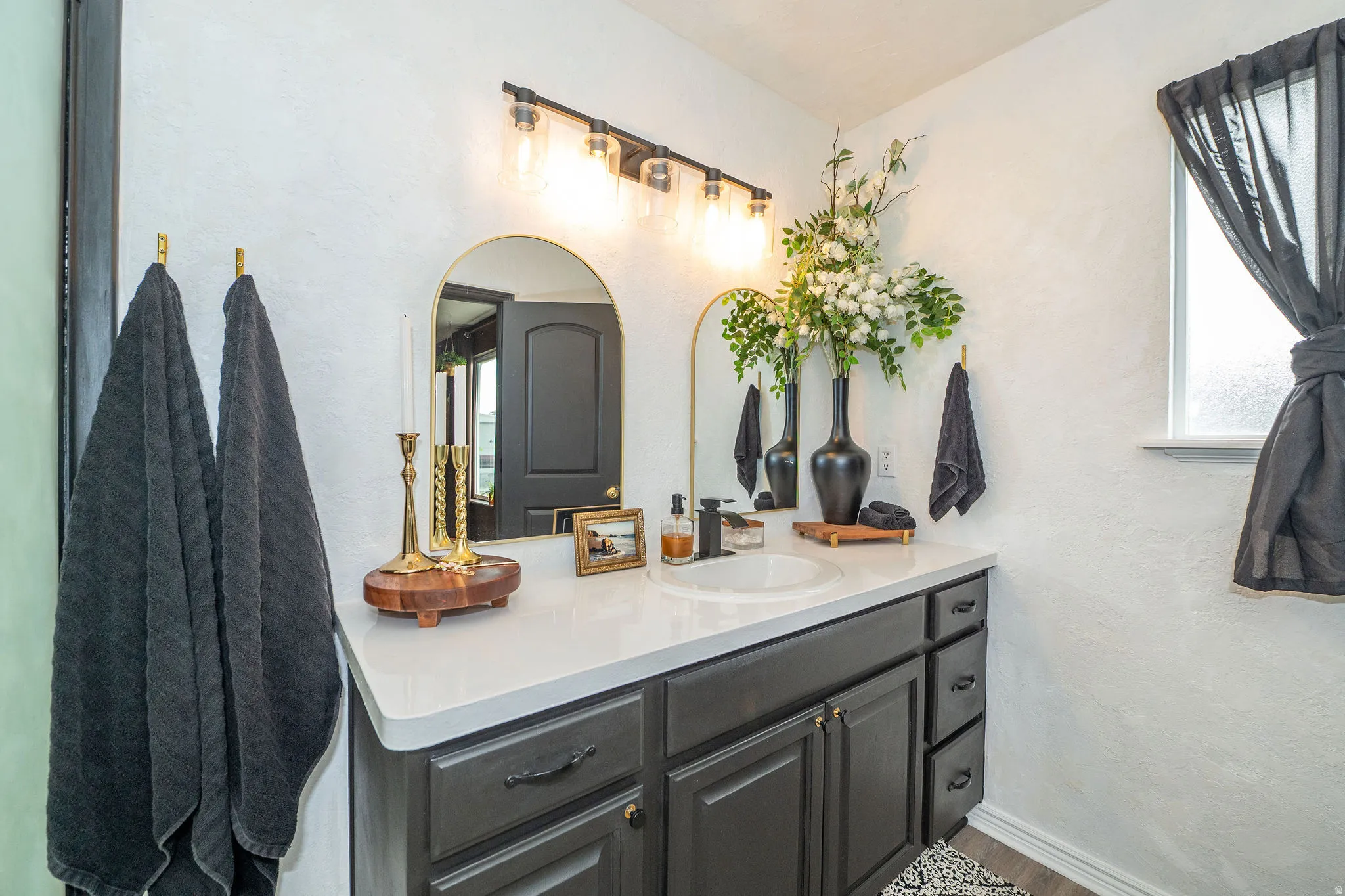 Bathroom vanity featuring a single basin sink, white countertop, and dark cabinetry with drawer storage