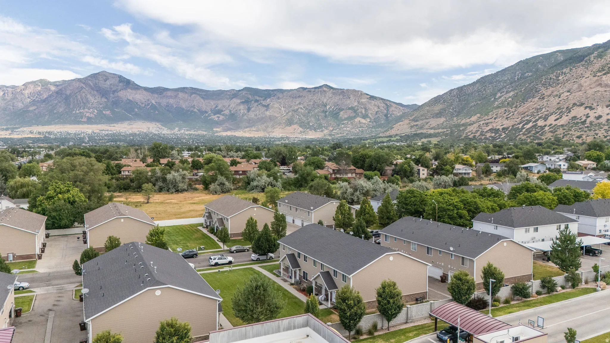 Townhome community featuring neutral-toned exteriors, dark shingle roofs, and green landscaping