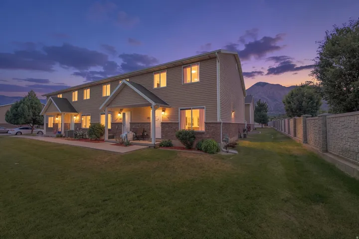 Two-story multi-unit dwelling with light tan siding and a brick-finish lower facade