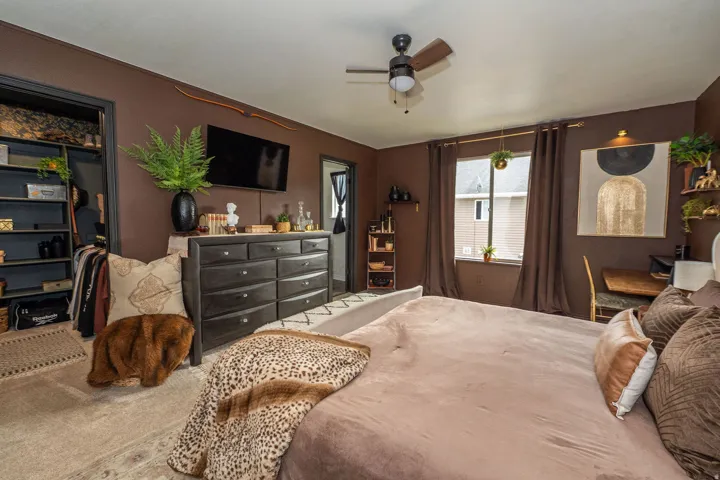 Bedroom featuring a ceiling fan, a window with curtain rods, a built-in closet with shelving,