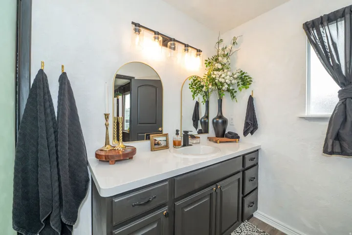 Bathroom vanity featuring a single basin sink, white countertop, and dark cabinetry with drawer storage