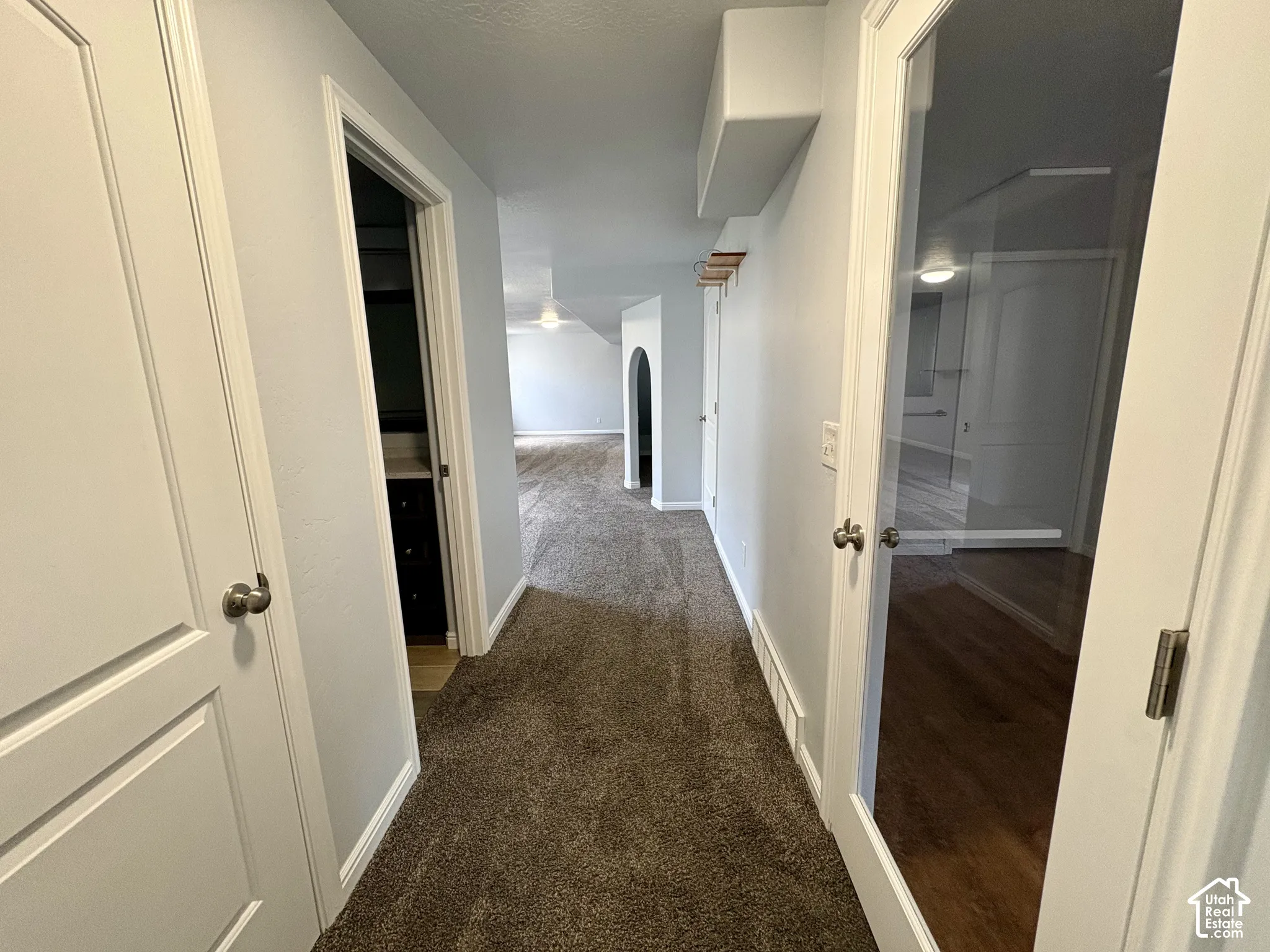 Hallway with textured carpet flooring, light gray wall paint, and white trim