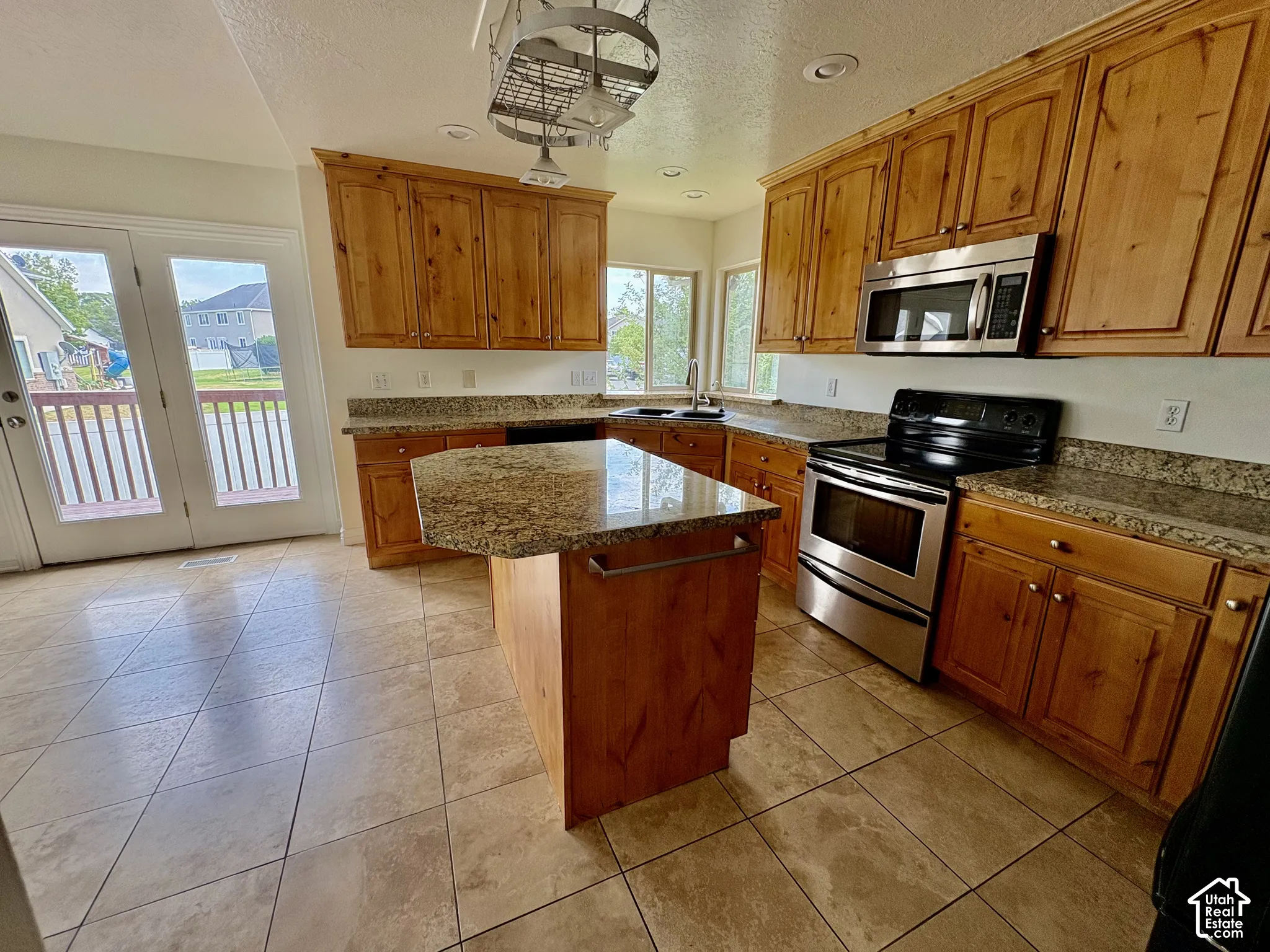Kitchen featuring wood cabinetry, an island with a countertop, stainless steel appliances, and a tile floor