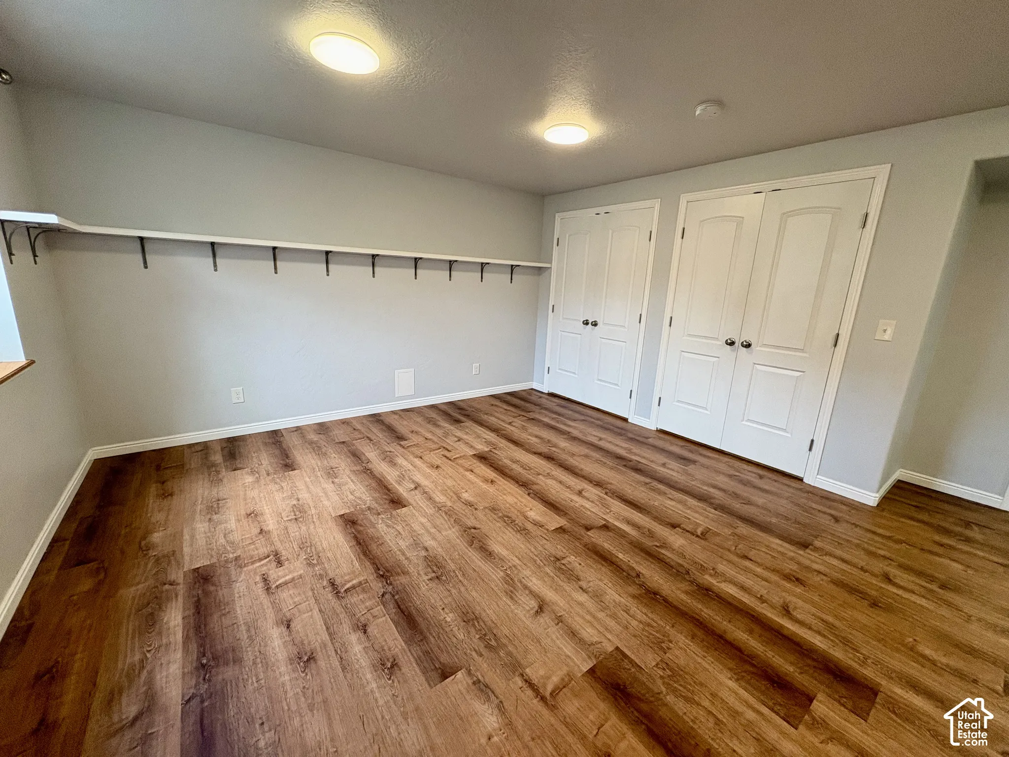 Spacious room featuring wood-finish flooring, light gray wall paint, and white trim