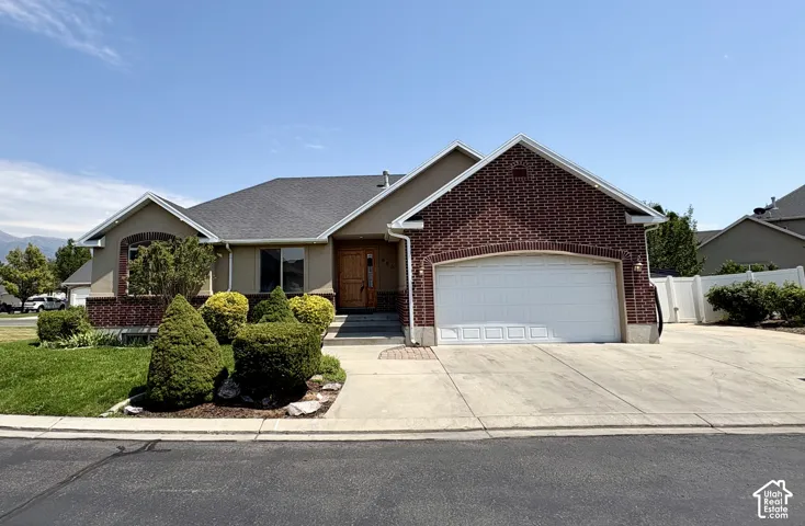 Brick and stucco exterior featuring an attached two-car garage with a white panel door, a concrete driveway, and a front walk leading to the entryway