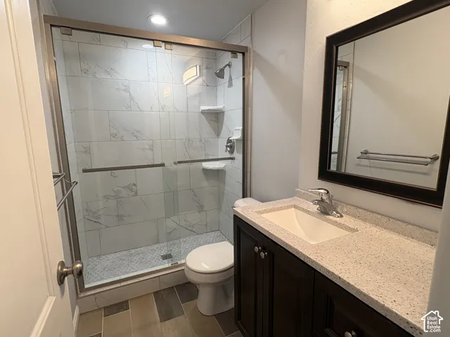 Bathroom featuring a glass-enclosed shower with white tiled walls and pebble-finish floor