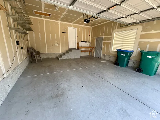 Spacious garage with concrete flooring, automatic overhead door, internal access via a separate door and concrete steps