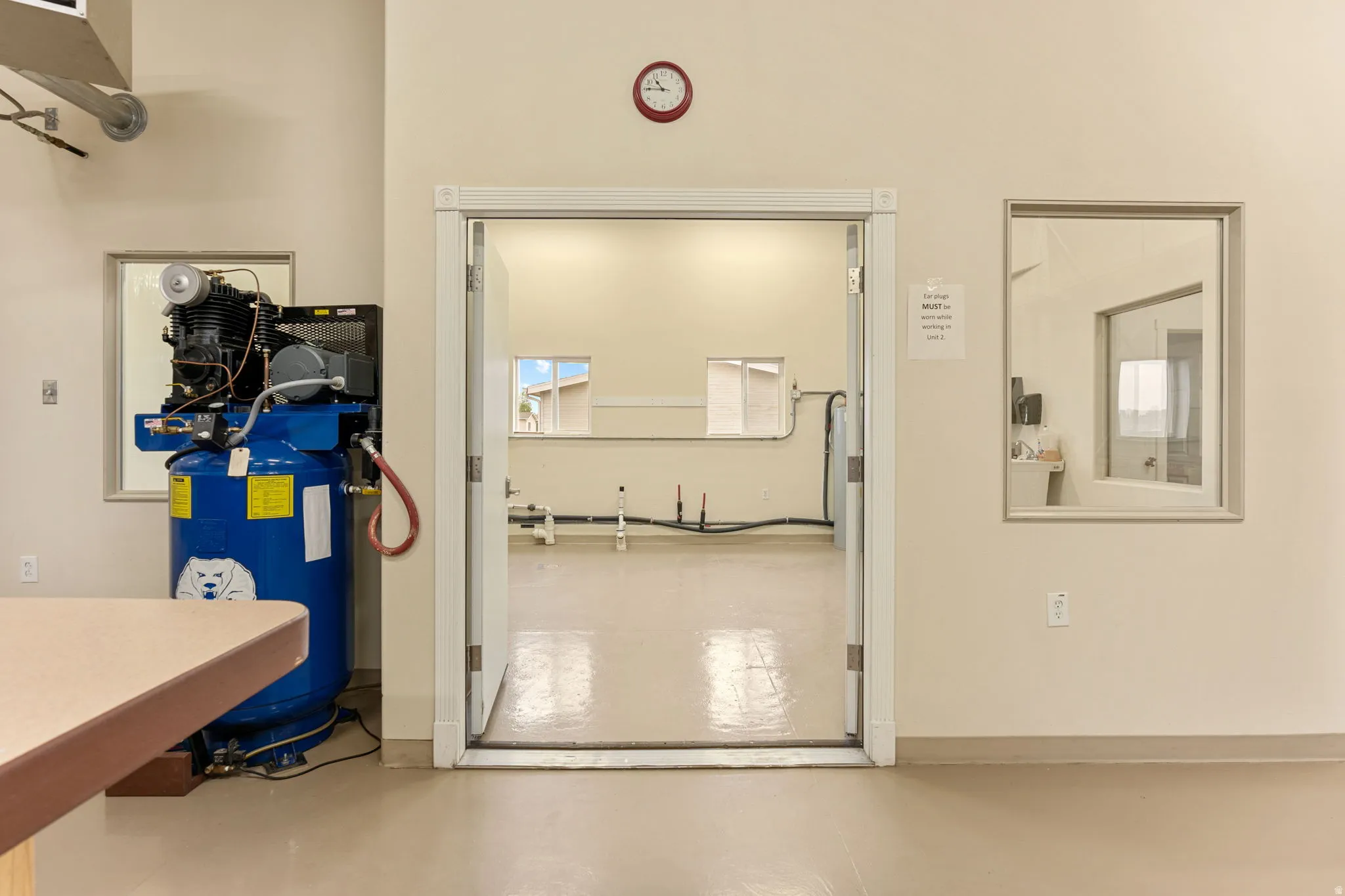 Bright interior space featuring a wide doorway, smooth light-toned flooring, and a large industrial air compressor