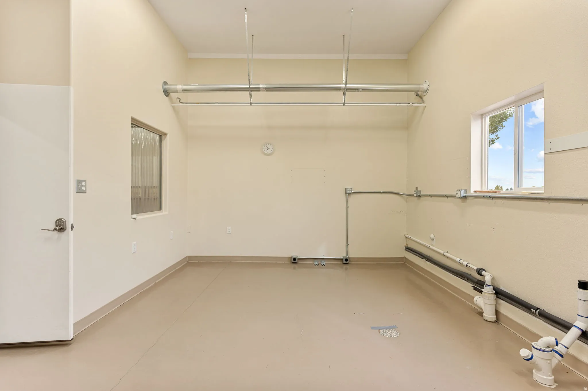 Spacious utility room featuring high ceilings, light-toned walls, and durable flooring with a cove base